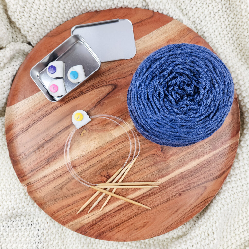 Colorful cord snaps in a silver tin on a wood and white knitted background with blue yarn.