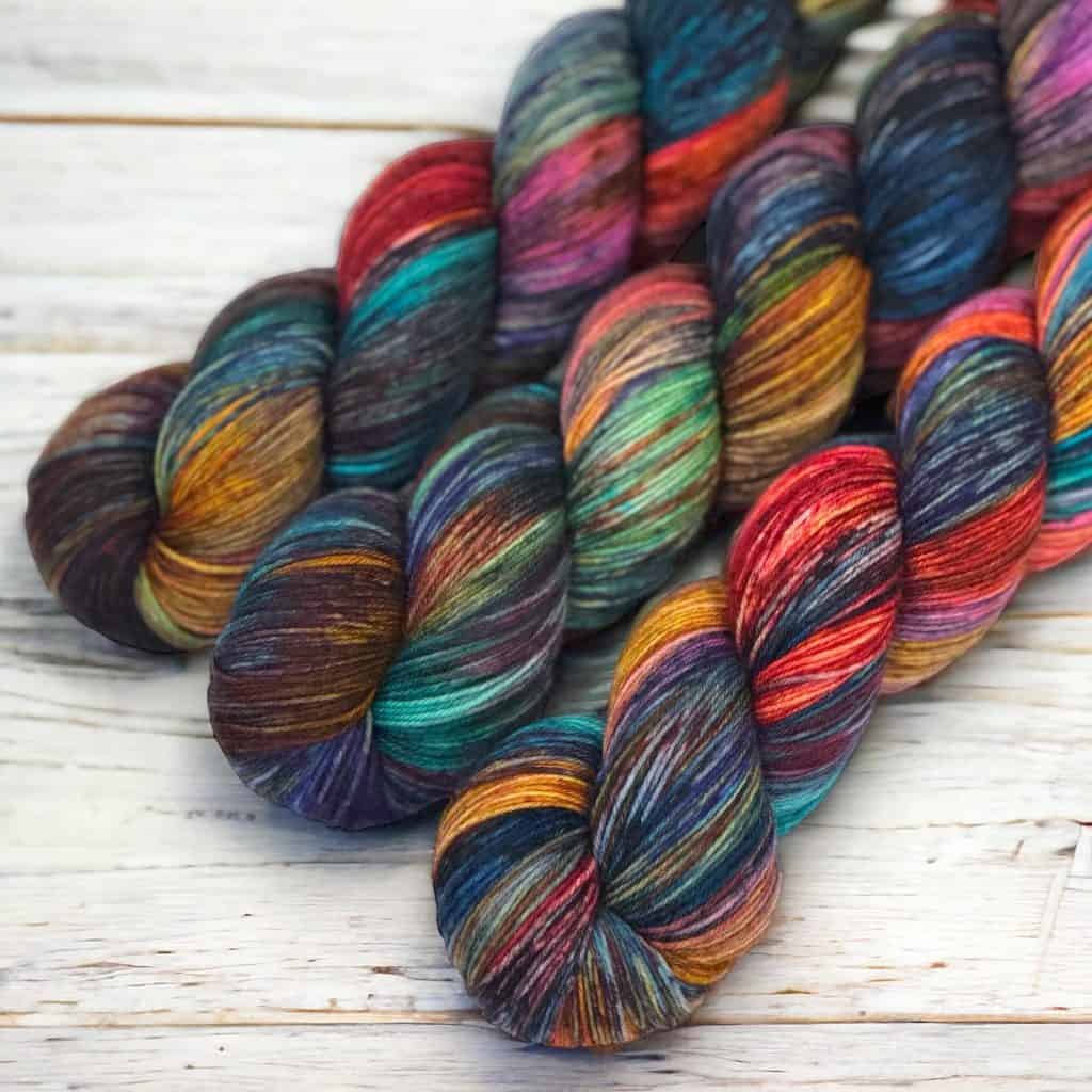 Multiple hanks of a multicolored yarn in gray, red, orange, blue and green.