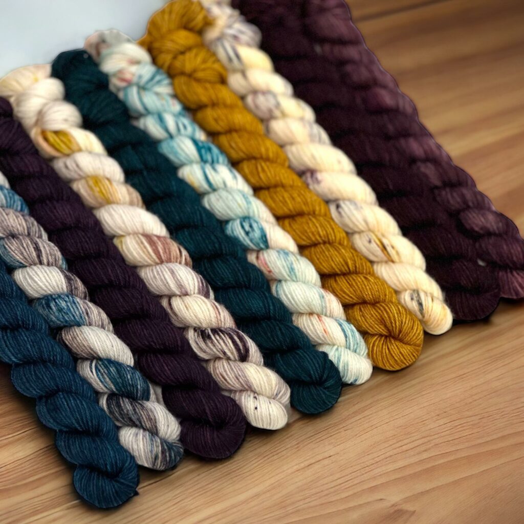 Ten mini hanks of yarn in teal, gold and raspberry brown.
