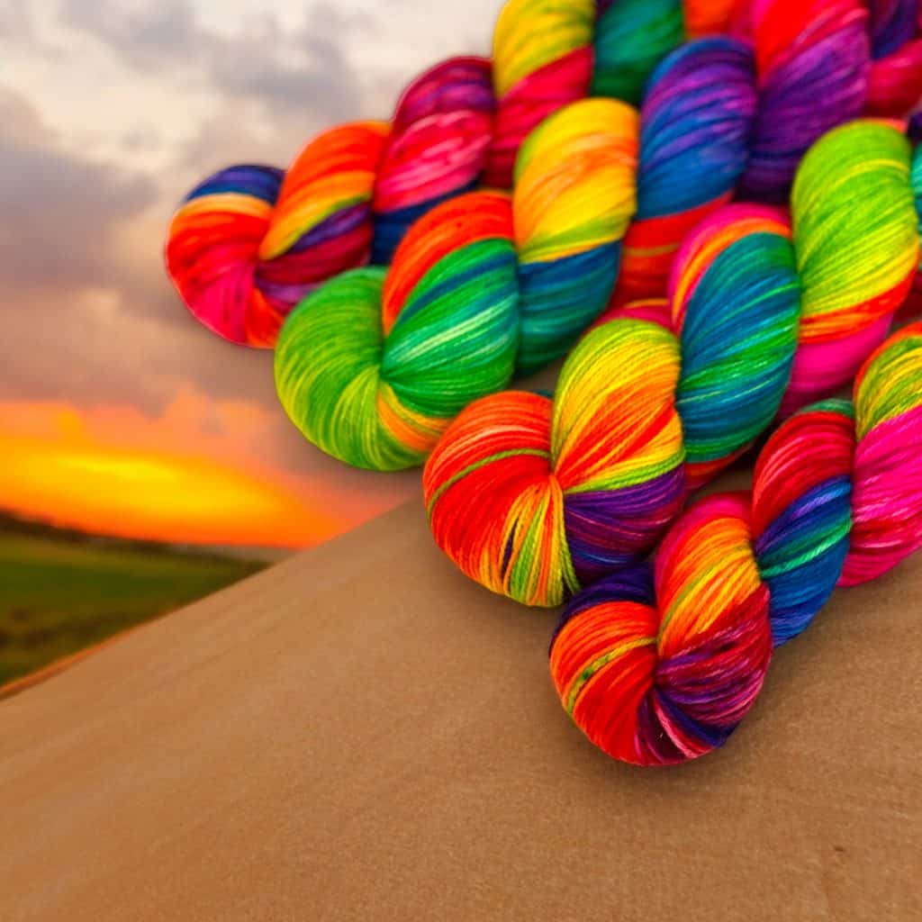 Four skeins of brightly colored yarn in front of a sunset.