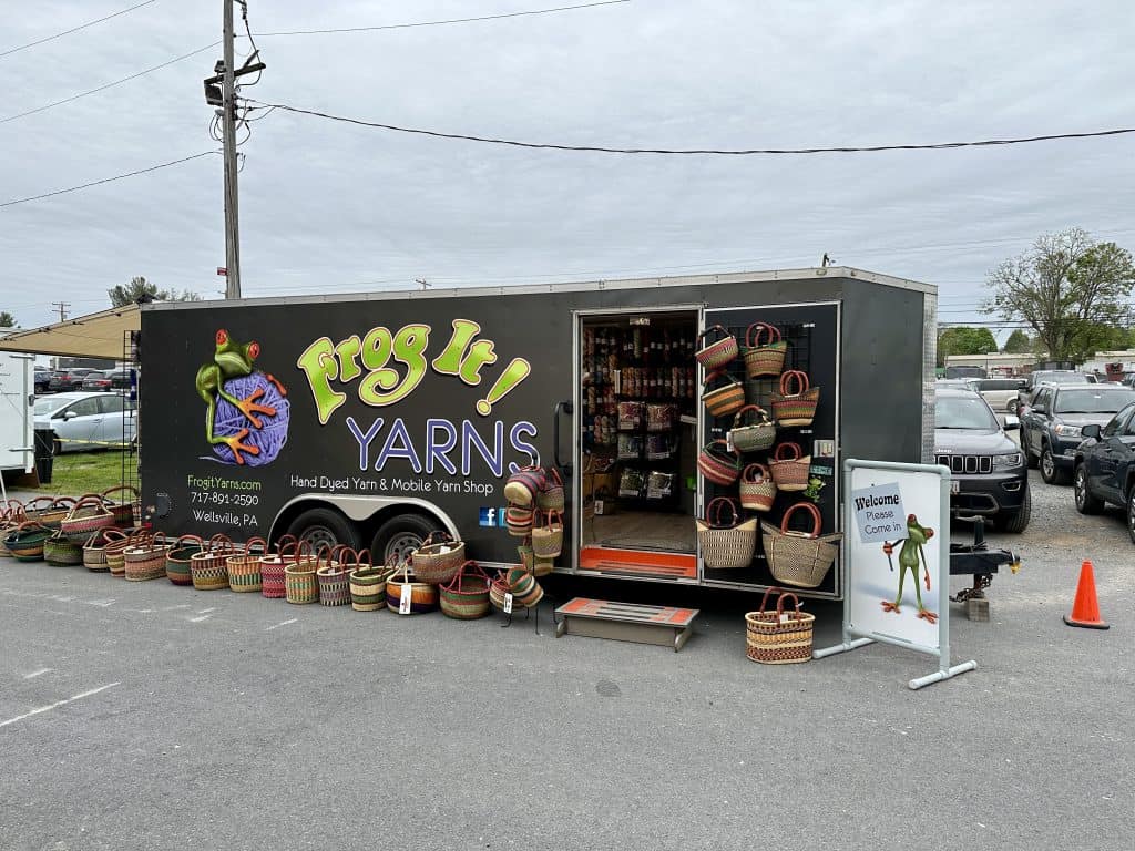 A trailer of yarn with baskets sitting outside.