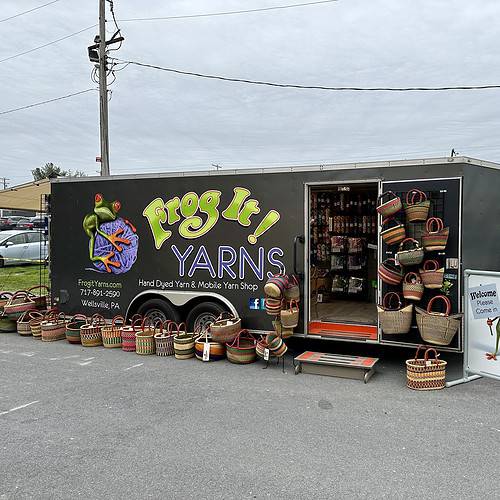 A trailer of yarn with baskets sitting outside.