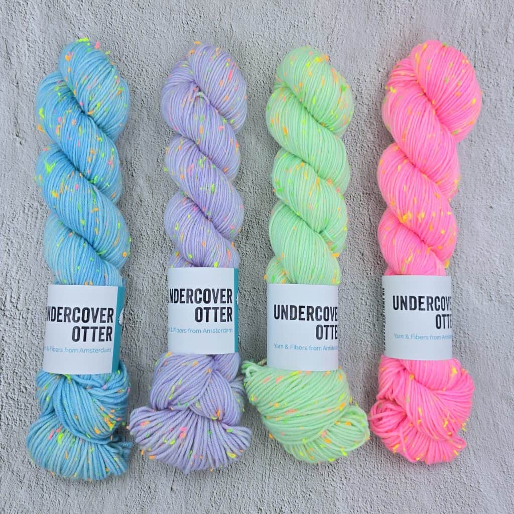 Skeins of bright blue, purple, green and pink yarn with neon nepps.