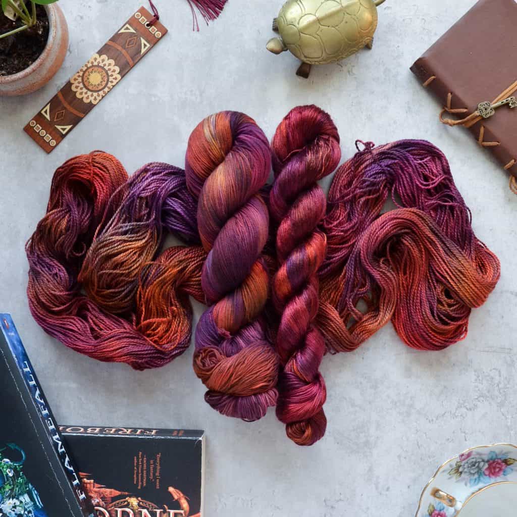 Two skeins of variegated red yarn over one unskeined variegated red yarn.