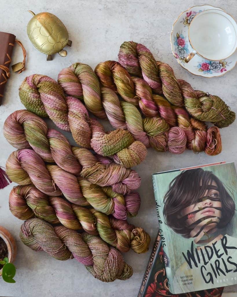 Eight skeins of pink, bronze, and green cotton yarn.