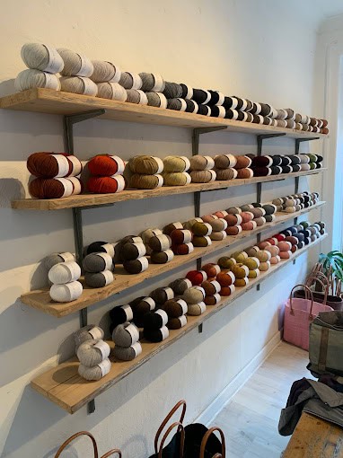 Interior of a store with yarn on a wall on shelves.