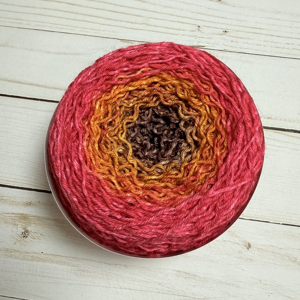 A cake of yarn in a red to purple gradient.