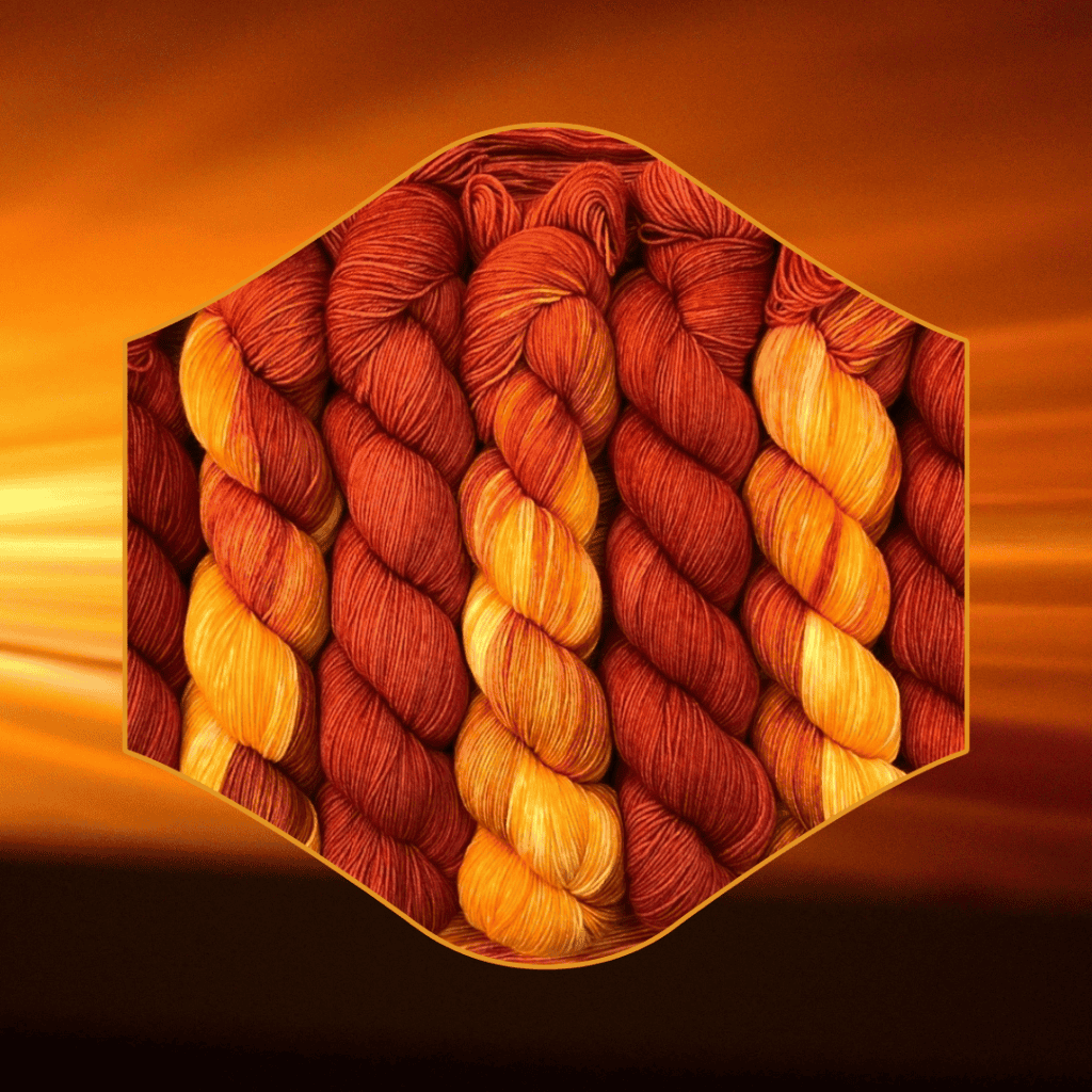 A photo of multiple hanks of deep orange and golden yarn against a sunset backdrop.