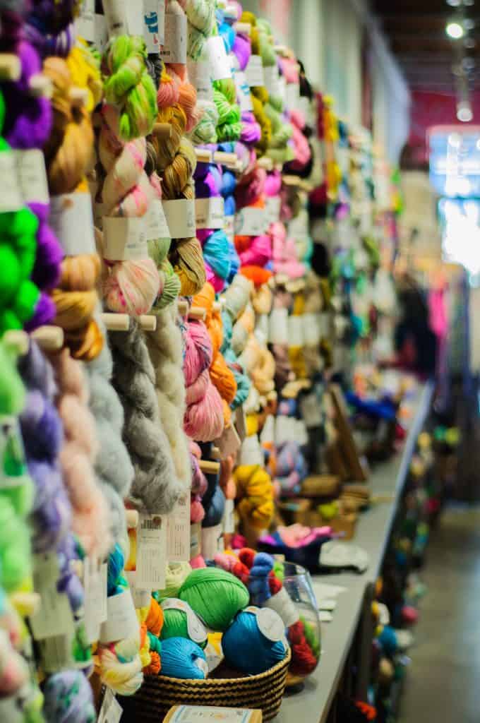 Wall stacked with vibrant skeins of yarn.
