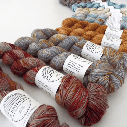 Red, gray, and amber skeins of yarn arranged in an arc.