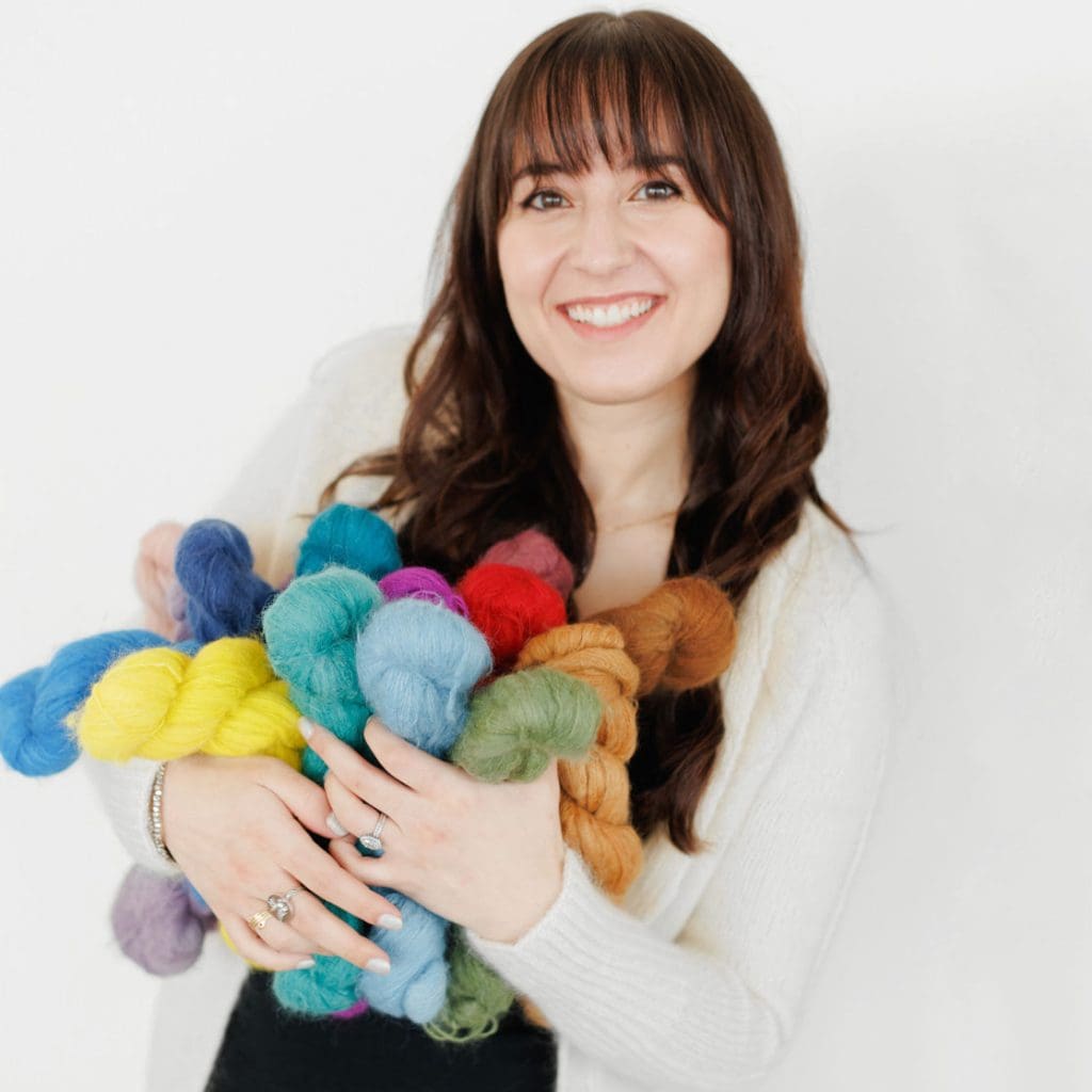 A woman holding a colorful pile of yarn