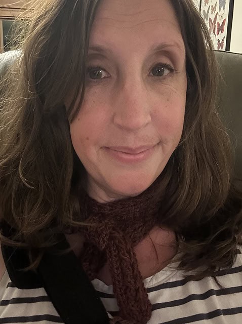 Light skinned woman wearing knitted brown scarf