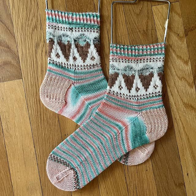 Knitted pink and greenish blue ice cream socks on wooden floor