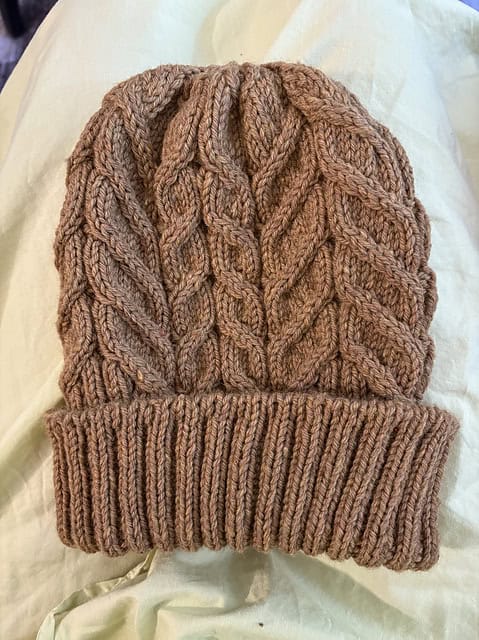 knitted brown hat on cream sheet