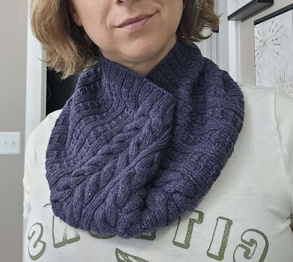 Light skinned woman wearing a soft, ribbed knit cowl in indigo over a cream sweatshirt