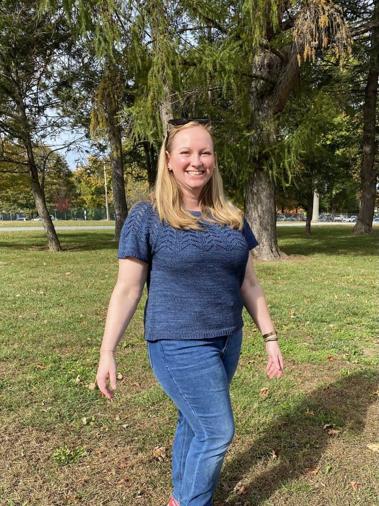Light skinned woman wearing blue knitted top outside