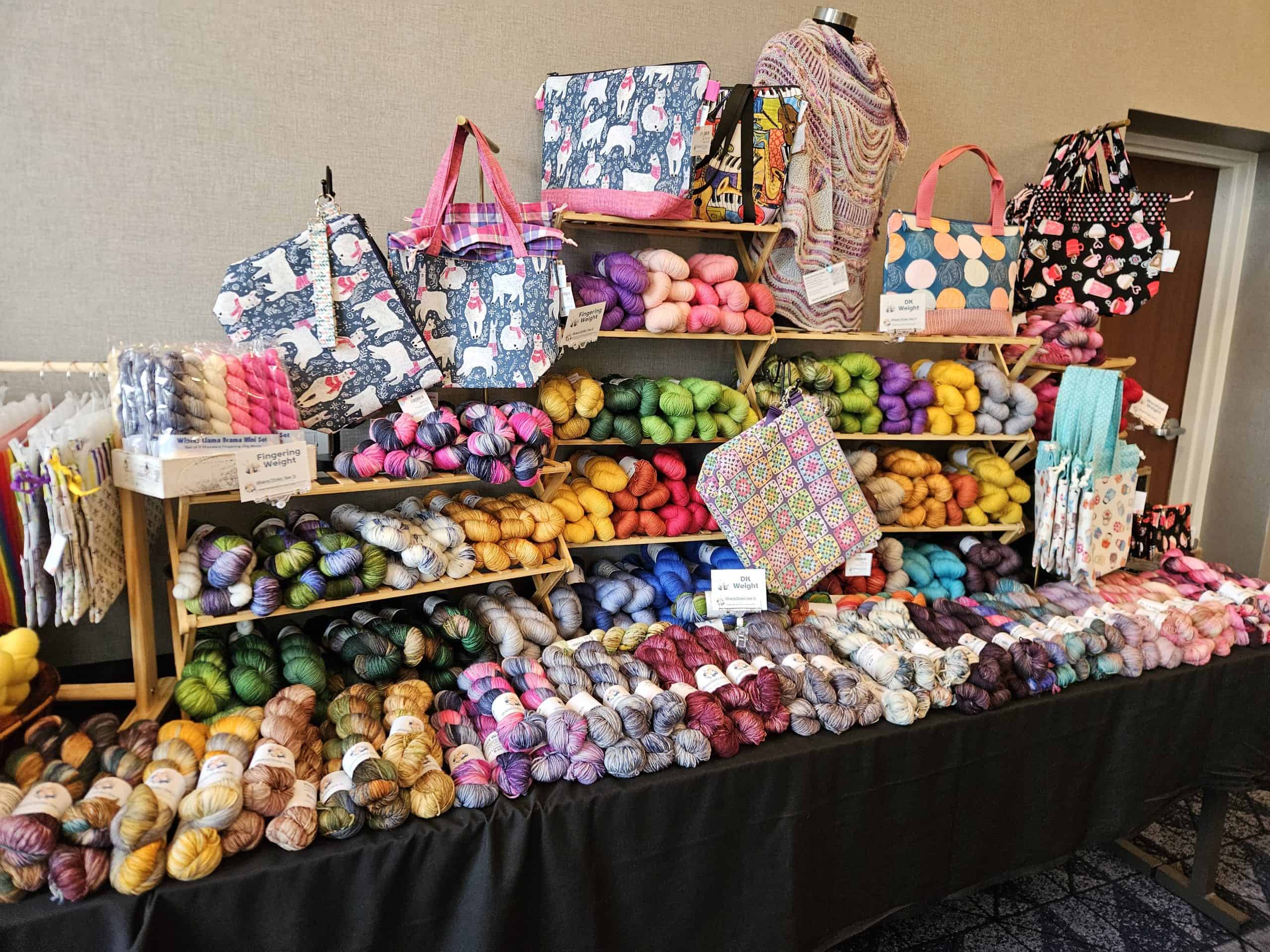 Display of colorful yarn, project bags and knit shawls.