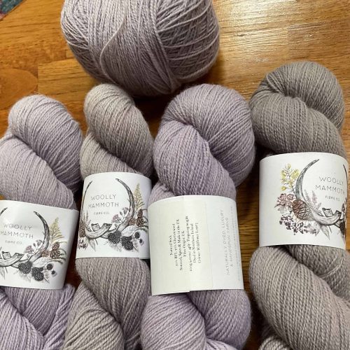 Four skeins of purple and gray yarn.