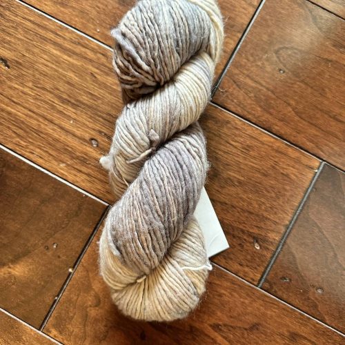 A skein of cream and brown worsted weight yarn.