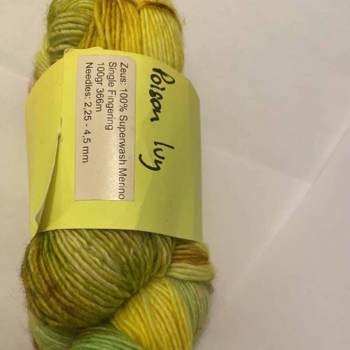 A skein of variegated hello, green and brown yarn showing spec from Tre Liz Zeus Poison Ivy.