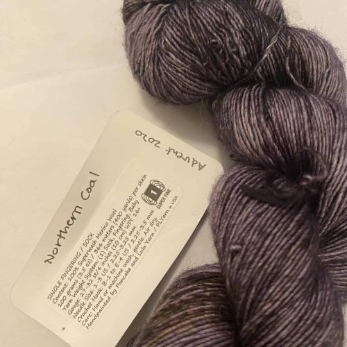 A skein of dark gray single-ply fingering weight yarn.