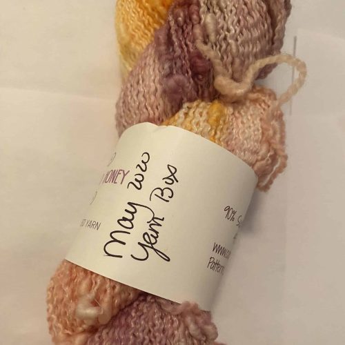 A skein of kinky purple, pink, orange and yellow variegated yarn.