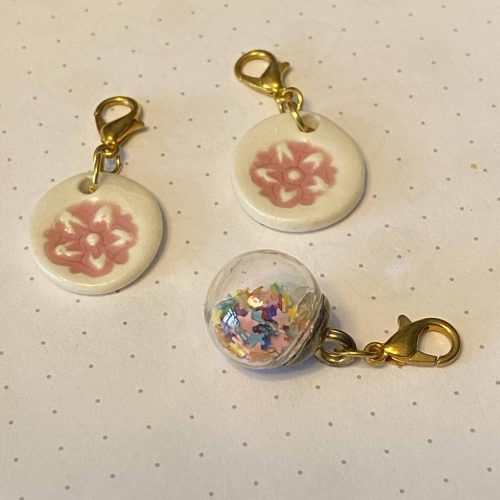 Set of 3 ceramic floral and glass with rainbow stars stitch markers.