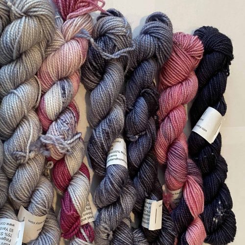 A set of 12 mini skeind of yarn in pinks and grays.