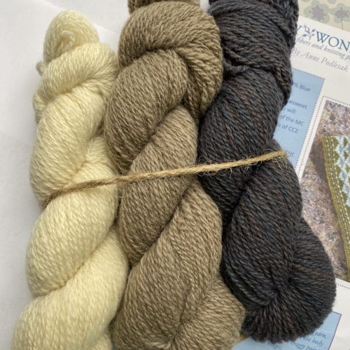 3 skeins natural, brown and gray yarn with cowl pattern.