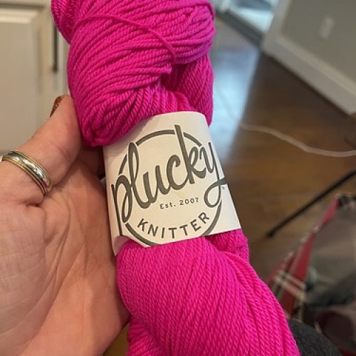 A skein of hot pink Plucky Knitter yarn.