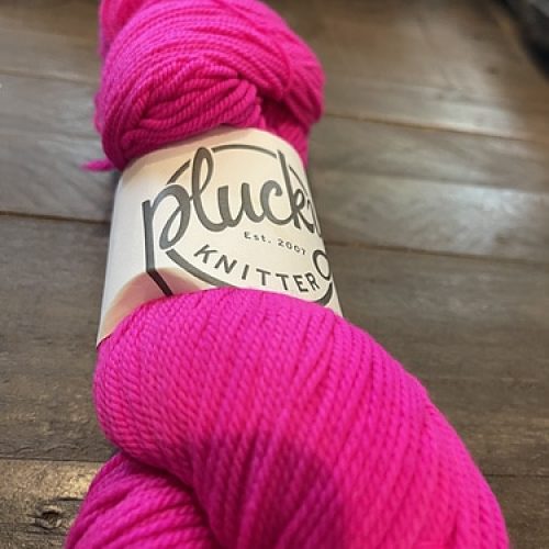 A skein of hot pink Plucky Knitter yarn.