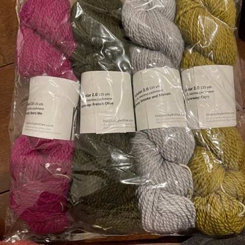Skeins of pink, green, gray and yellow yarn.
